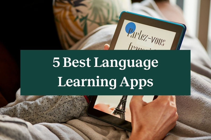 A person relaxing and holding a tablet while reading from one of the best language learning apps