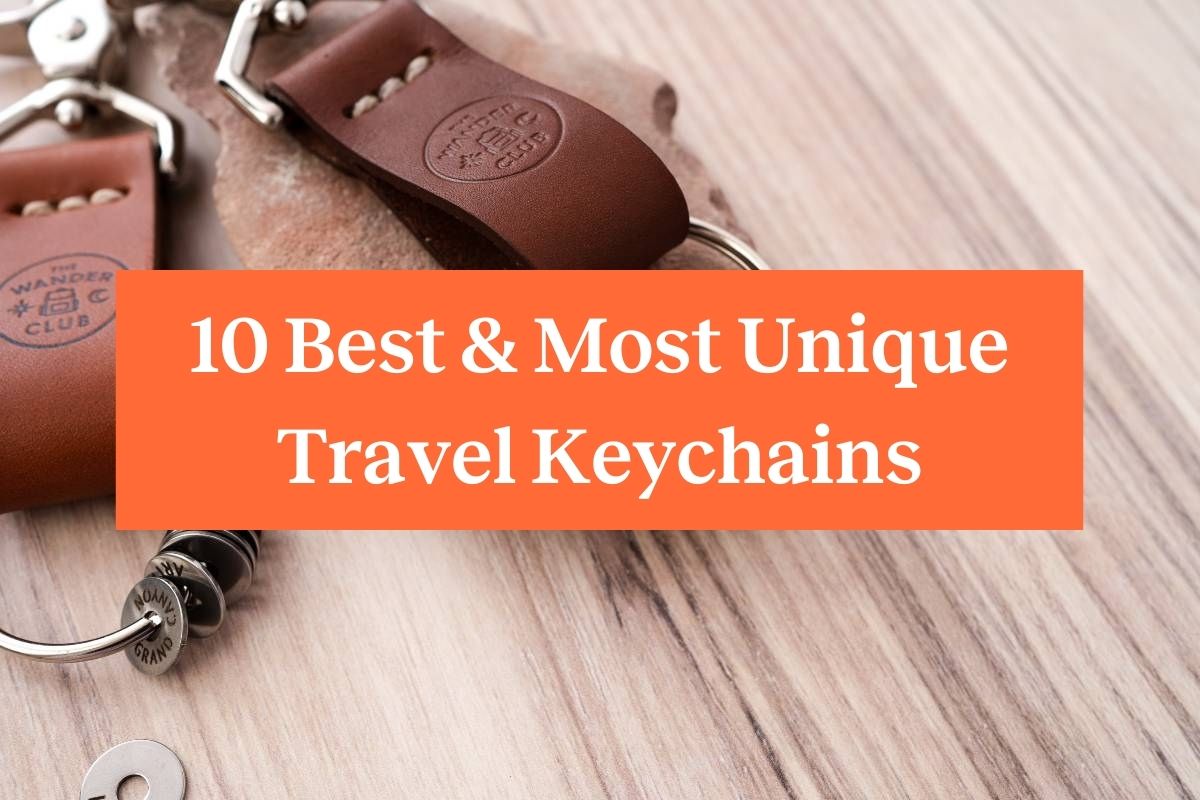 Two brown Wanderchains with Travel Tokens against a wood background and an orange rectangle with white letters saying "10 Best & Most Unique Travel Keychains"